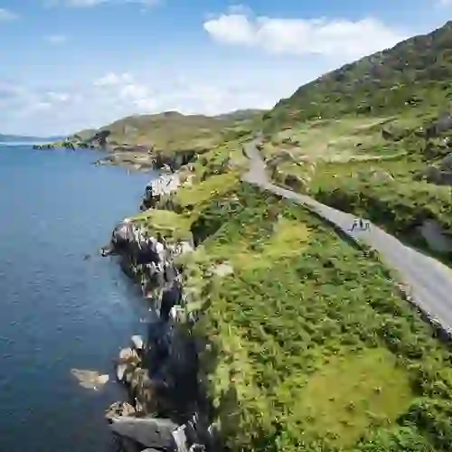 Scenic coastal road on the Beara Peninsula, County Cork, with walkers enjoying sea views and rugged green hills.