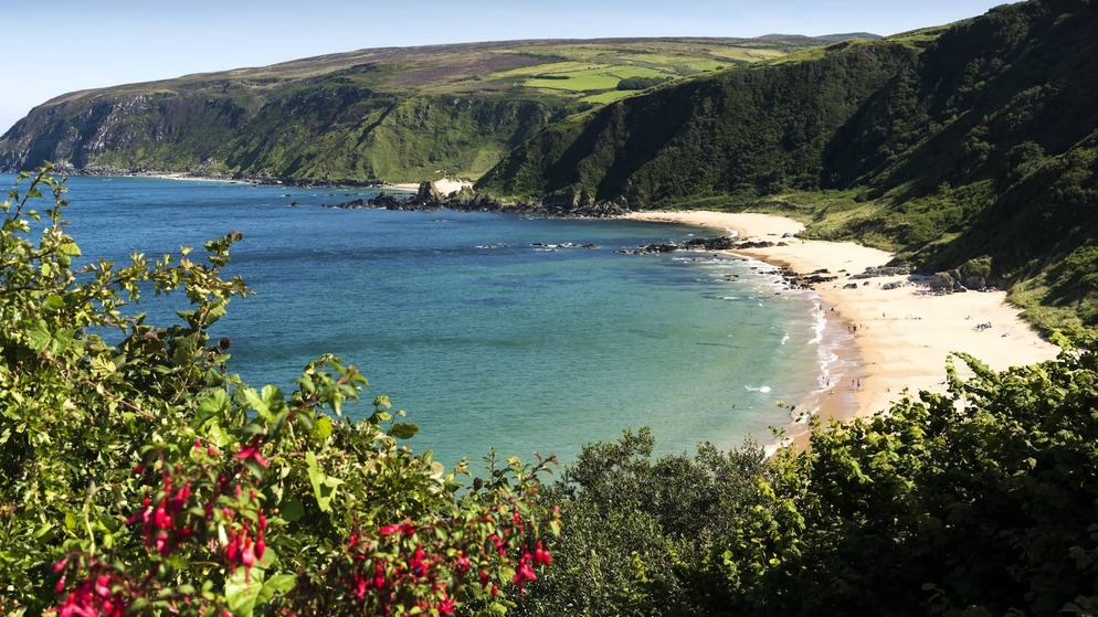 Coastal road above Keem Bay, Achill Island, with turquoise water, sandy beach, and green hills.