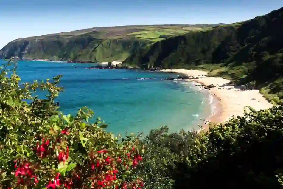 Coastal road above Keem Bay, Achill Island, with turquoise water, sandy beach, and green hills.