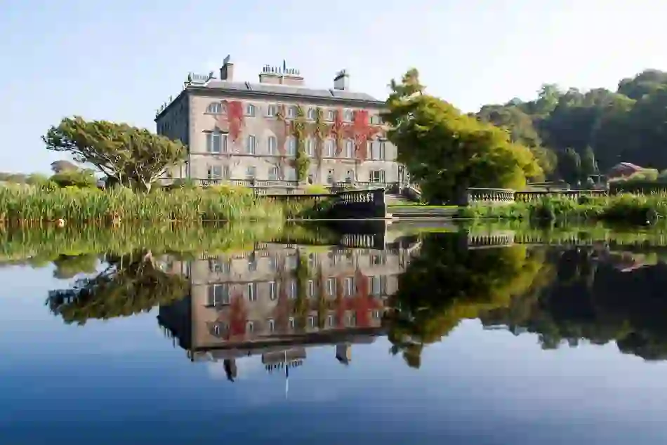 Elegant Westport House in County Mayo reflected in a still lake, surrounded by lush gardens and mature trees.