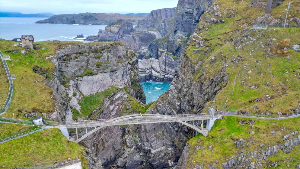 Aerial view of the dramatic Mizen Head cliffs with a pedestrian bridge spanning a deep sea gorge along the Wild Atlantic Way.