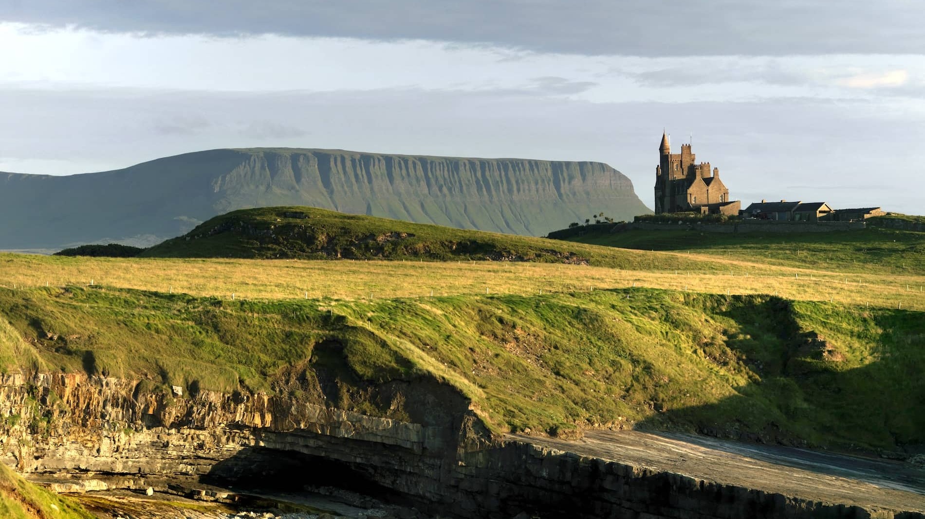 Classiebawn Castle perched on green headland with Ben Bulben mountain in the background, County Sligo.