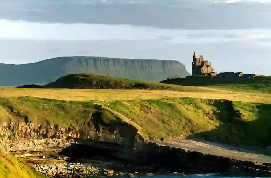 Classiebawn Castle perched on green headland with Ben Bulben mountain in the background, County Sligo.