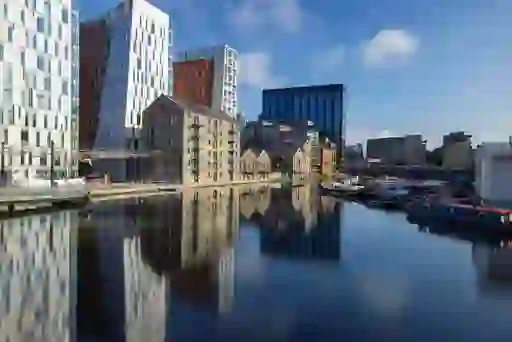 Contemporary glass buildings reflect in Grand Canal Dock beside converted warehouses and moored barges in Dublin.