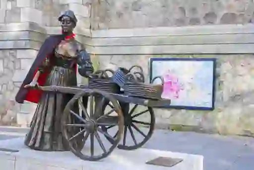 Molly Malone statue wearing a Halloween cape with a cart of baskets in Dublin city centre.