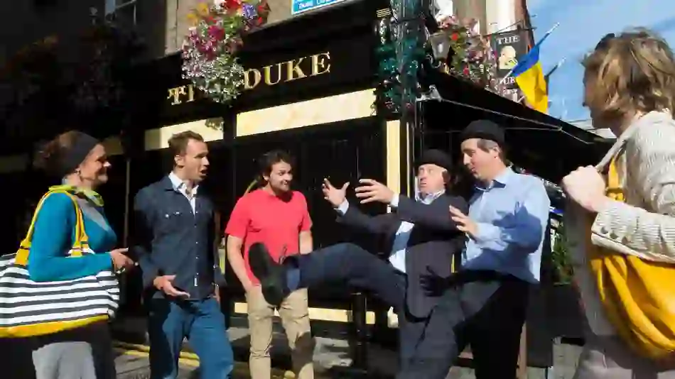 Street performers entertain a group outside The Duke pub in Dublin on a literary walking tour.