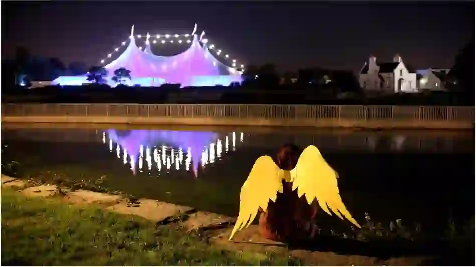 Night view of Galway International Arts Festival tent lit in purple, reflected in the River Corrib.