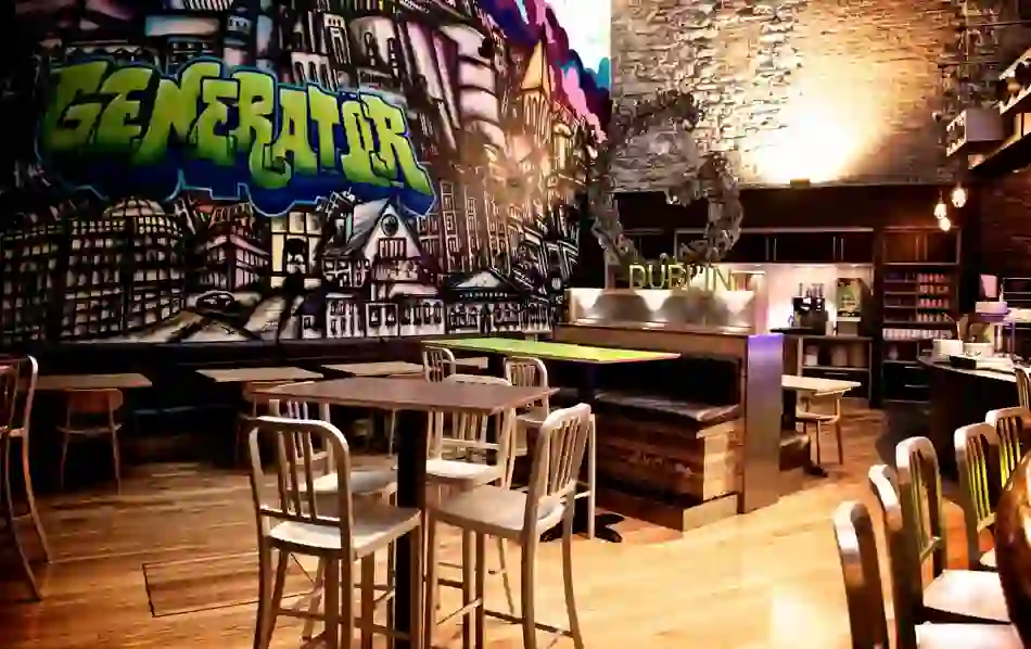 Colourful graffiti mural inside Generator Hostel Dublin with tables and chairs in the dining area.