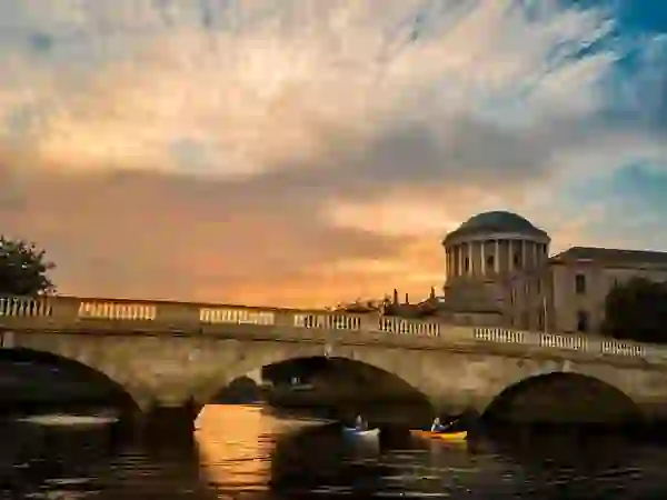 Two kayakers on the River Liffey with the Four Courts in Dublin at sunset.