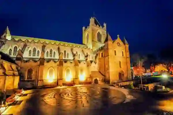 Christ Church Cathedral in Dublin illuminated at night against a dark blue sky.