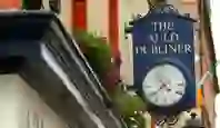 The Auld Dubliner sign with a vintage-style clock hanging over the entrance, surrounded by flowers in Temple Bar, Dublin.