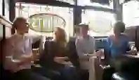 Four friends sitting inside O’Neill’s Pub on Suffolk Street, Dublin, with stained-glass windows behind them reading ‘Spirits’.