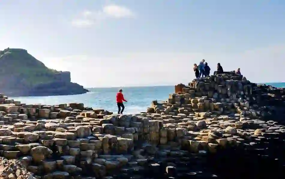 People exploring the Giant’s Causeway in County Antrim with waves crashing against the basalt columns.