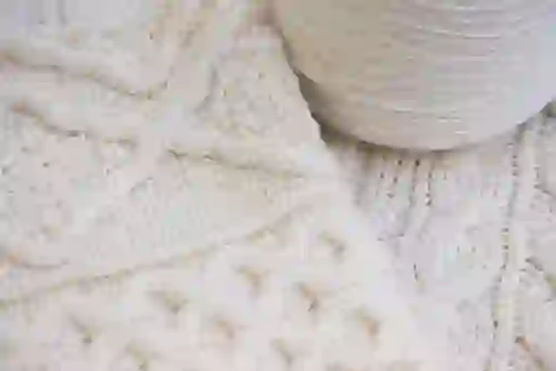 Traditional Aran knit patterns in undyed wool showcased alongside a spool of yarn – a celebration of Galway’s craft heritage.