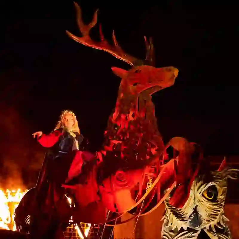 Performer in red cloak riding a giant deer sculpture at Samhain Festival, County Longford, Ireland.