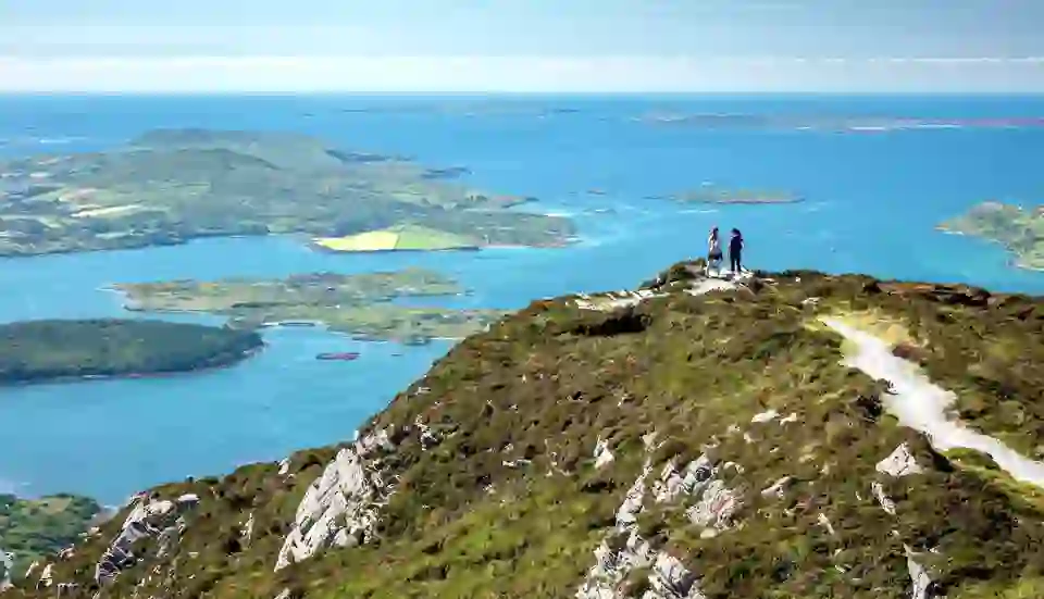 Hikers on Diamond Hill trail overlooking the Connemara coastline and islands in County Galway.