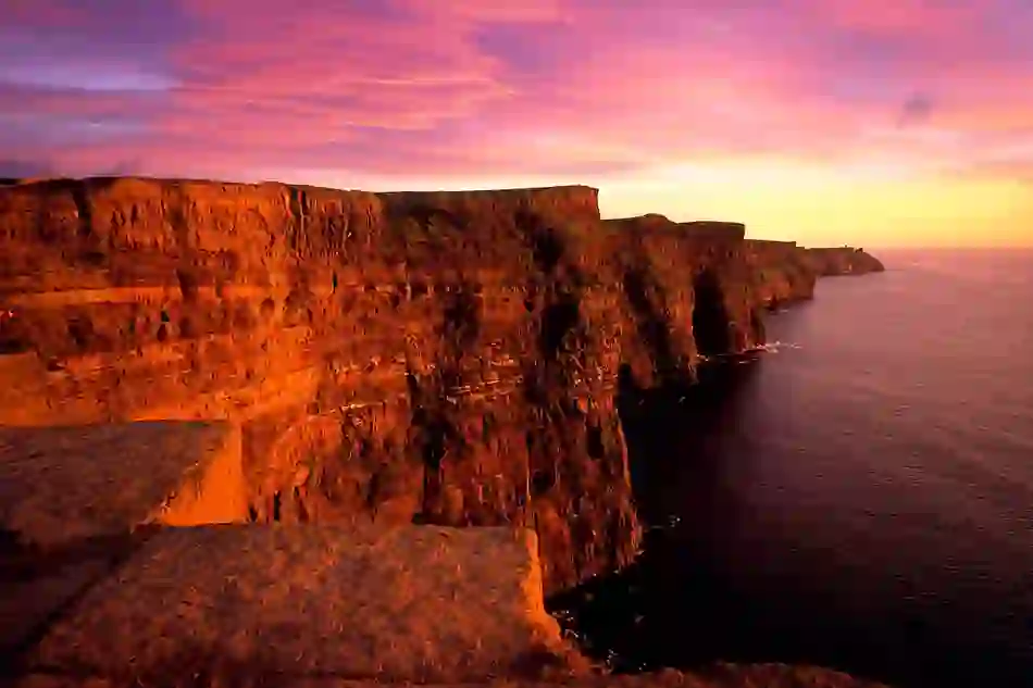 Cliffs of Moher glowing in the sunset light along the Wild Atlantic Way in County Clare, Ireland.