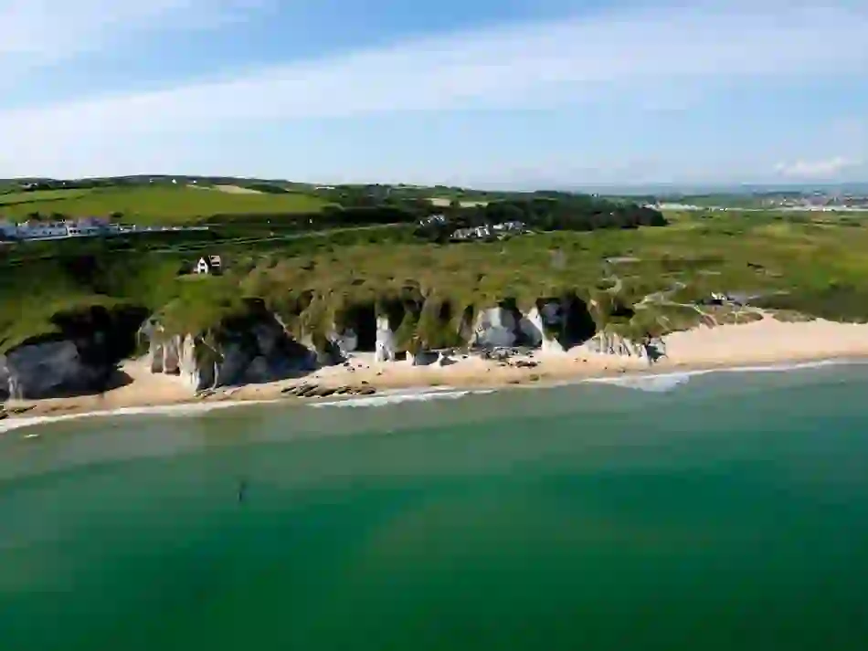 White sandy beach backed by cliffs near Portrush in County Antrim with walking trails leading along the coastline.