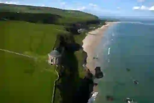 Mussenden Temple perched above Downhill Strand beach in County Londonderry with grassy cliffs and a long sandy shoreline.