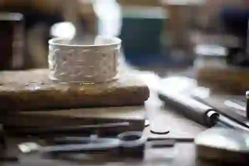 Close-up of handcrafted silver ring with Celtic knot design on a jeweller’s workbench in Kilkenny Design Centre.