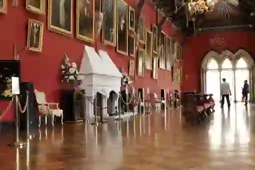 Ornate Long Gallery inside Kilkenny Castle with red walls, portraits, chandeliers and wooden floor.
