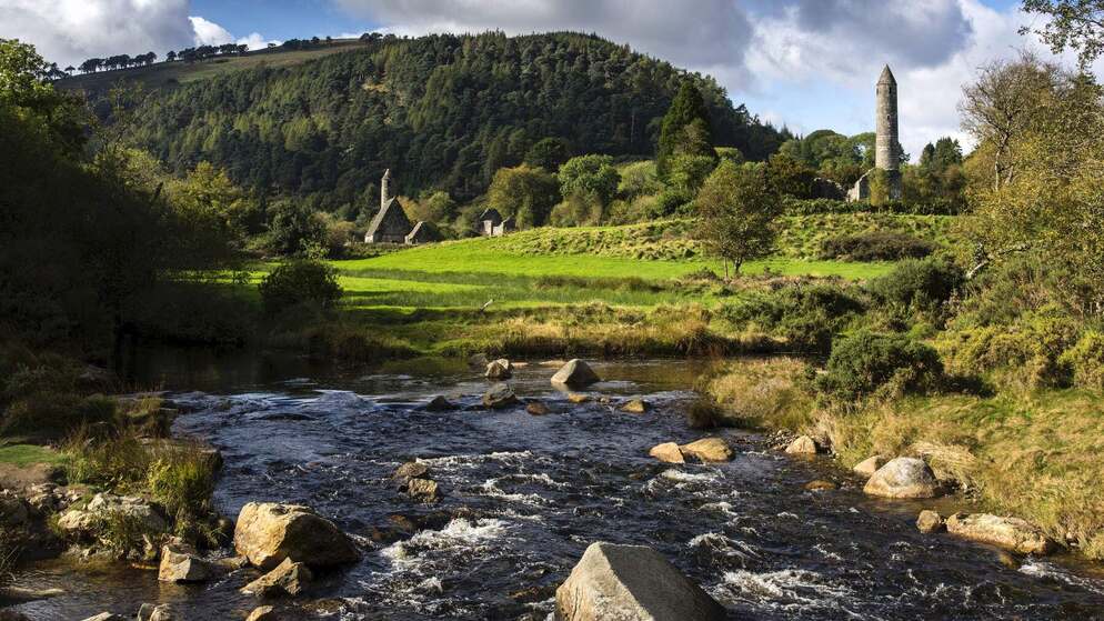 Ancient round tower and stone church at Glendalough Monastic City in County Wicklow, Ireland.