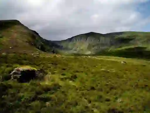 Rolling green slopes and rocky cliffs of the Comeragh Mountains in County Waterford.