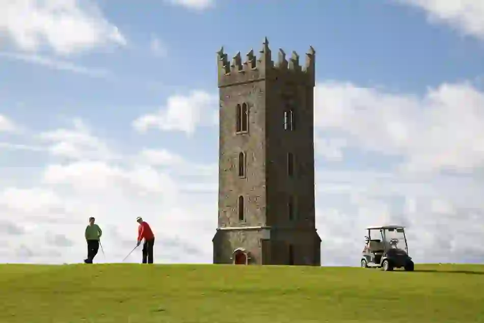 Carton House Golf Course, County Kildare, featuring a tall stone tower and golfers playing nearby.