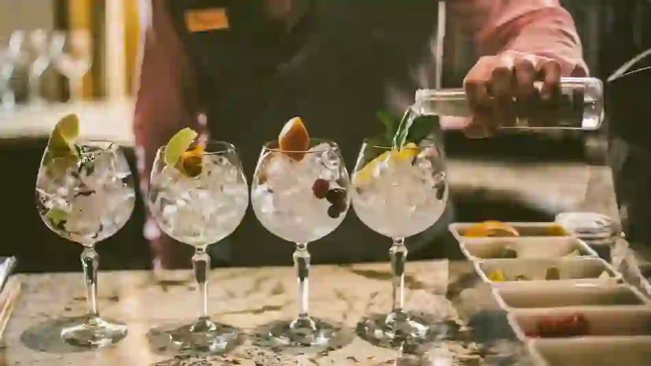 Bartender pouring tonic into gin and tonic glasses with fruit garnishes at Galgorm Resort in County Antrim.