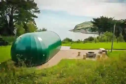 A modern green pod at Glenarm Castle, County Antrim, overlooking the sea and Causeway Coast cliffs.