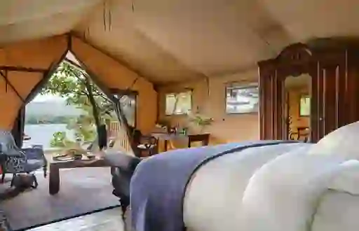 A luxury safari tent at Dromquinna Manor, County Kerry, with antique furniture and views of Kenmare Bay.