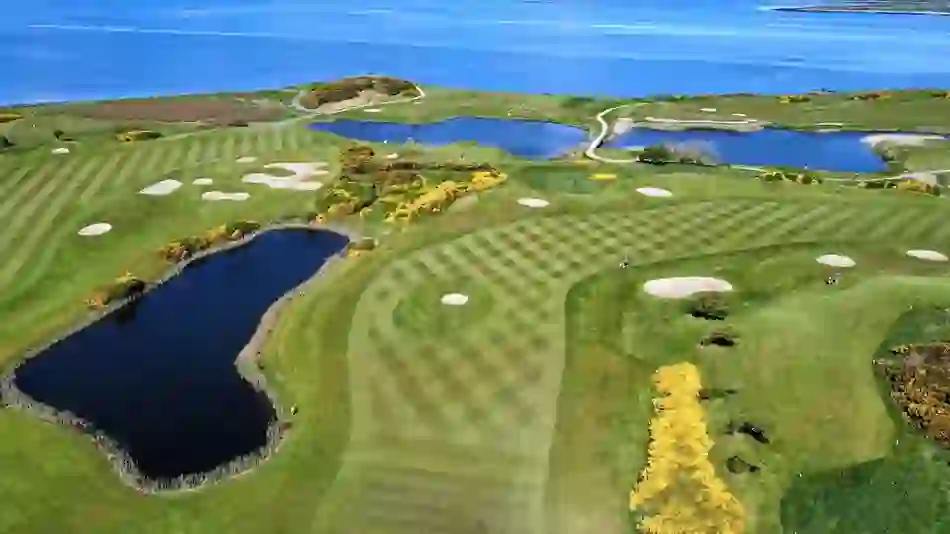 Galway Bay Golf Resort, County Galway, with striped fairways, lakes, and Atlantic Ocean backdrop.