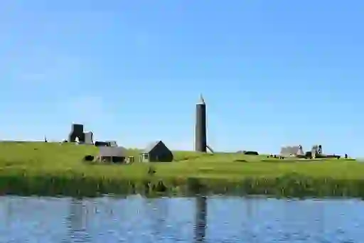 Devenish Island with a round tower and medieval ruins rising above green fields beside Lough Erne.