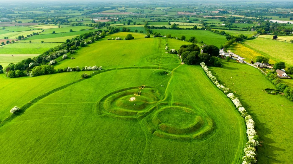 Aerial view of the Hill of Tara’s ancient earthworks surrounded by lush Meath countryside under a clear sky.