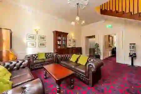 Traditional drawing room with leather sofas, wood furniture and red carpet in the Castle Hotel, Dublin.