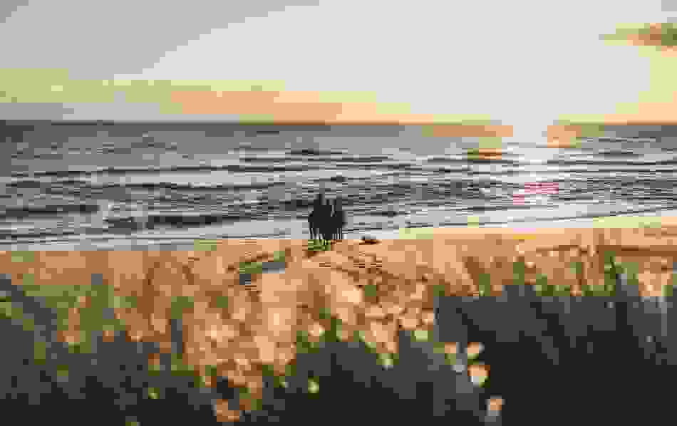 Horse riders on the beach at Brittas Bay, County Wexford, at sunrise with waves rolling onto the shore.