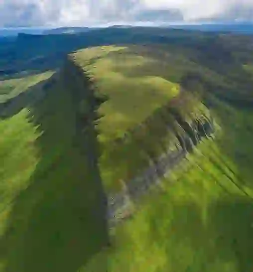 Aerial view of Ben Bulben’s flat-topped peak in County Sligo, its dramatic limestone cliffs surrounded by rolling green hills.