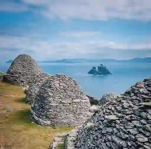 Stone beehive huts of Skellig Michael overlooking the Atlantic, with Little Skellig island visible in the distance.