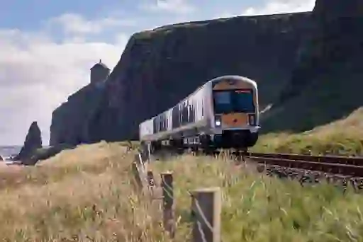 Train running past Mussenden Temple and cliffs along the Causeway Coast in Northern Ireland.