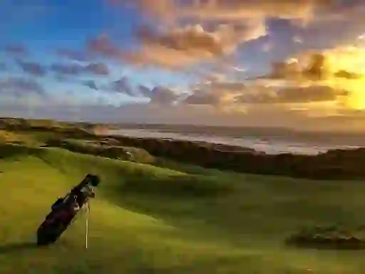 Golf bag on a coastal links course at sunset, representing Irish golfer Shane Lowry.