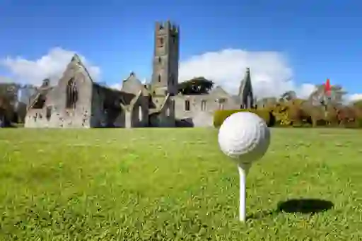 Golf ball on a tee with the ruins of a stone abbey in the background, representing Paul Dunne.
