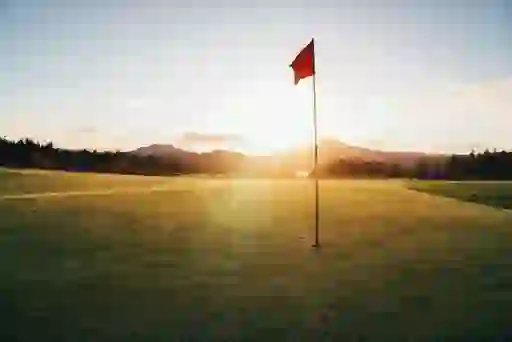 Flag on a golf green at sunset with mountains in the distance, representing Padraig Harrington.