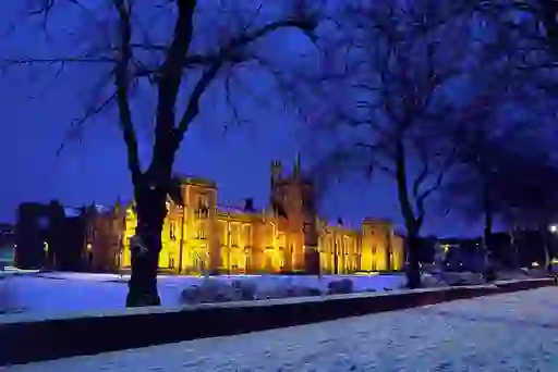 Queen’s University Belfast glowing warmly against a snowy winter evening.