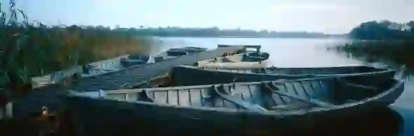 Row of wooden boats moored to a narrow jetty on the still waters of Lough Erne, County Fermanagh.