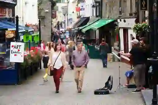 Visitors strolling along Kilkenny’s Medieval Mile with street musicians performing.