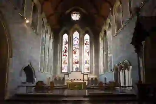Interior of St Canice’s Cathedral with stained glass windows and stone arches.