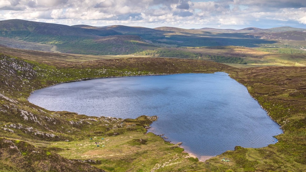 Lough Tay in County Wicklow surrounded by hills and open skies, featured in a story about Irish romantic legends.