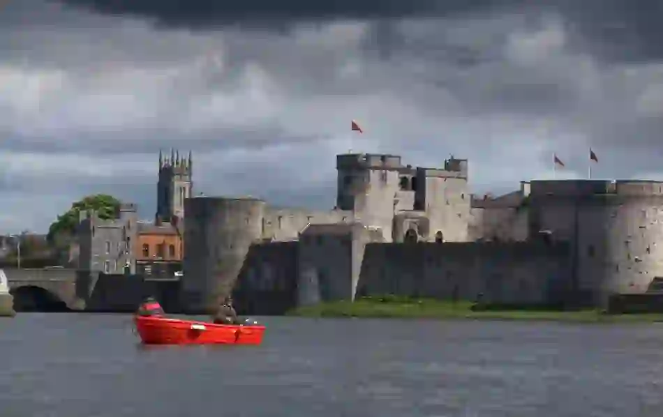 Fishermen in a red boat on the River Shannon with King John’s Castle in the background.