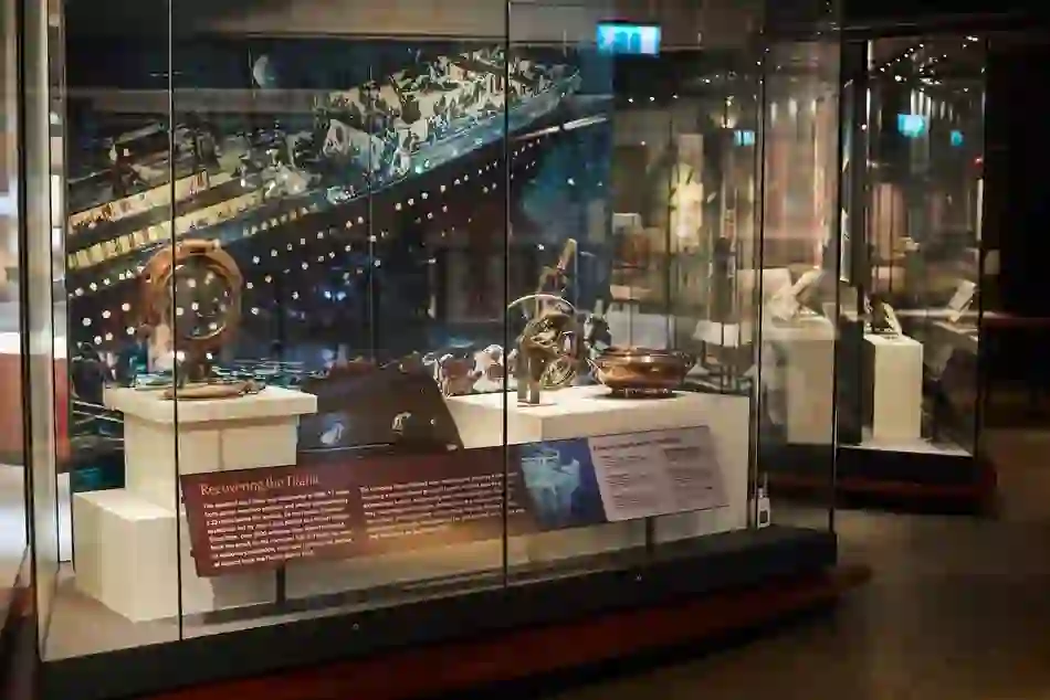 Display of recovered Titanic artefacts, including a porthole and navigation instruments, in a museum case.