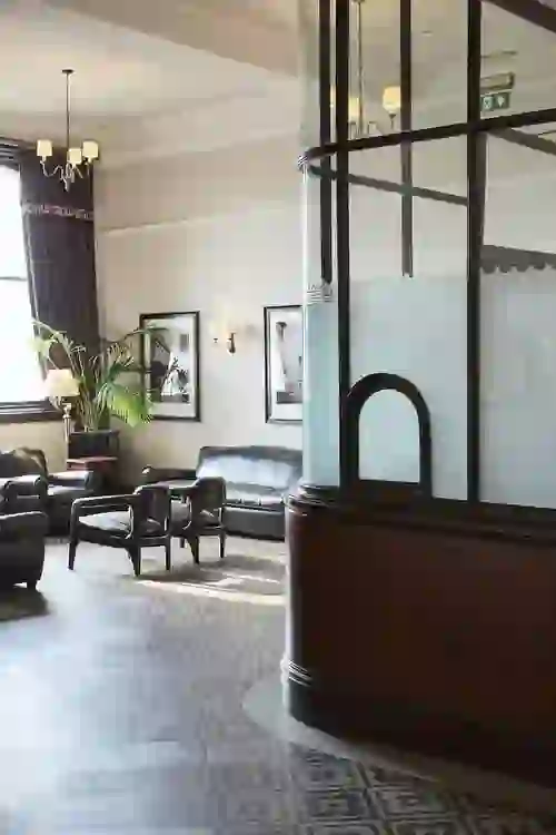 Vintage booth and leather armchairs in the Titanic Hotel, Belfast, with framed photos and soft lighting.